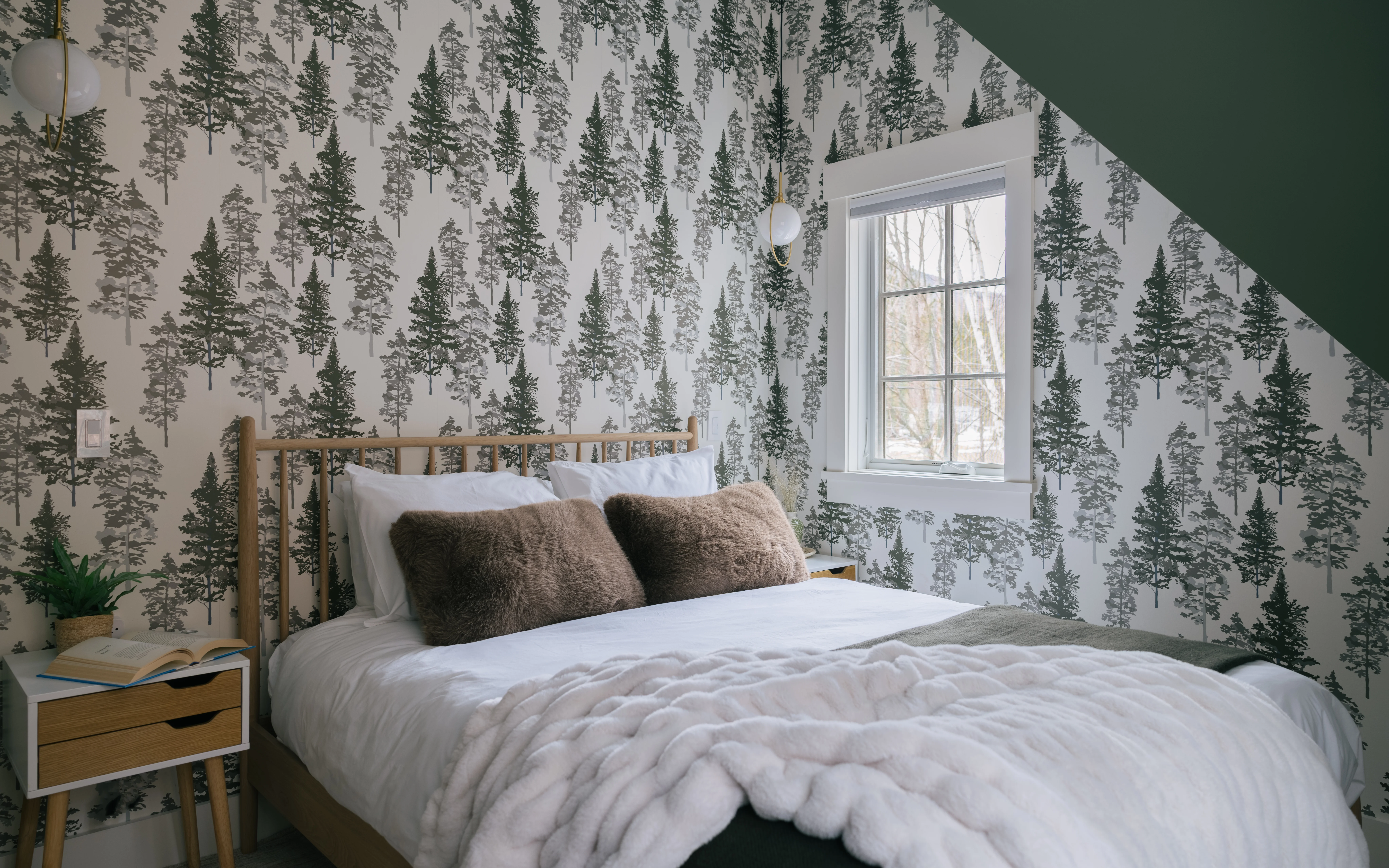 Guest house bedroom with comfortable bedding, warm lighting, and Vermont-inspired decor